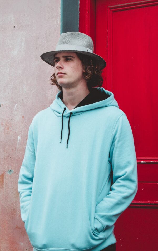 boy with a hat and teal hooded sweatshirt looking to the side